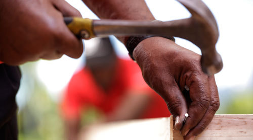 AGS Movers packer closing a wooden crate with a hammer and a nail.